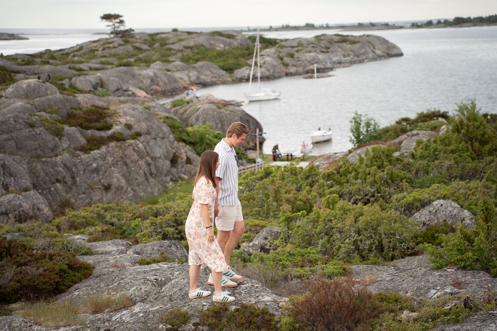 Couple on the granite rocks of an island in the Stockholm archipelago, reached by private boat for a proposal